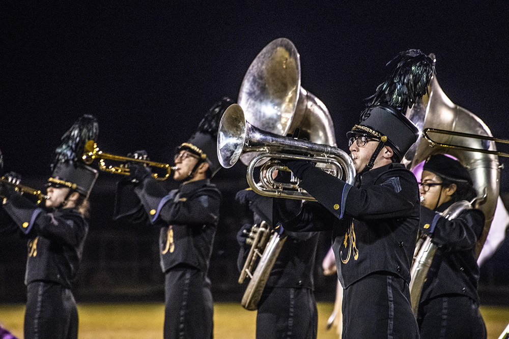 Several students play brass instruments while dressed in marching band uniforms.