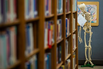 Books line shelves while a skeleton hangs in the background.