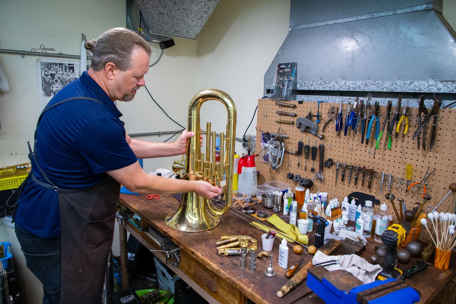 Technician repairs a french horn.