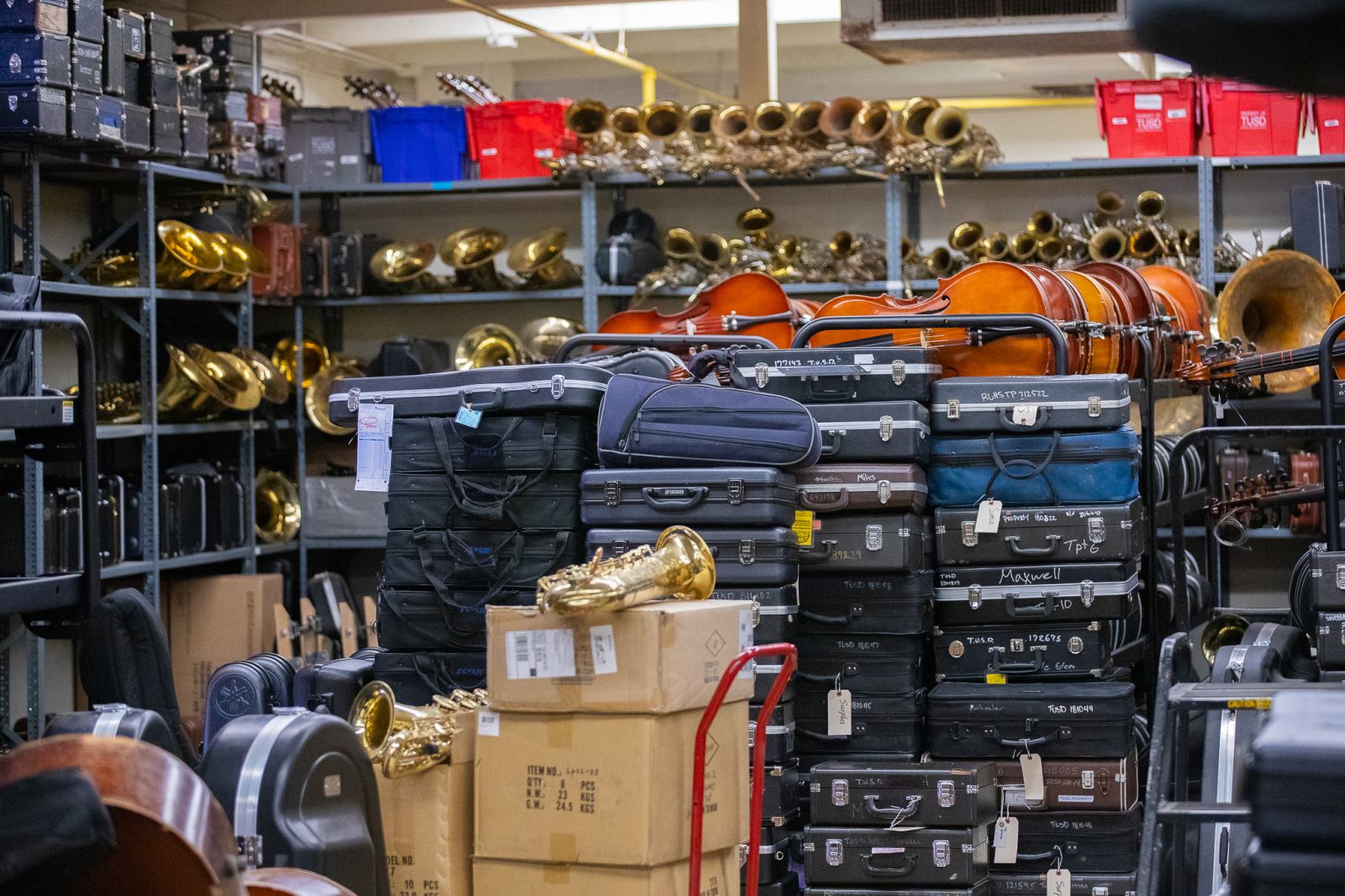 Instrument cases are stacked in front of shelves full of instruments.