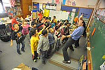 Teacher excitedly performs in front a classroom of first graders.